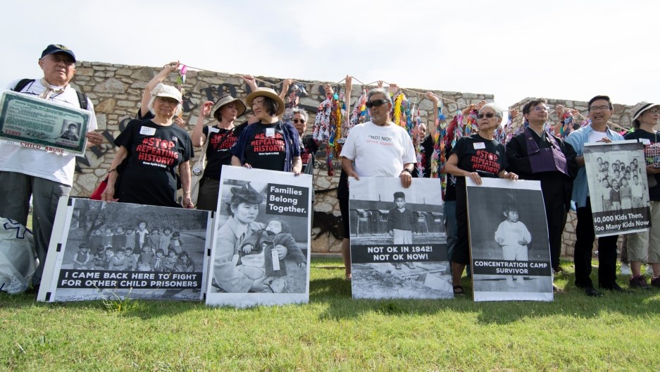 A group of protesters stand in a line holding signs protesting family separation and incarceration of migrants