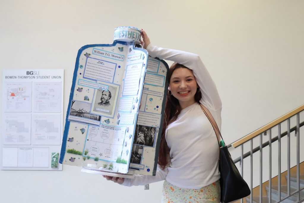 image of student holding up a 3 dimension exhibit with text about anesthetic 
